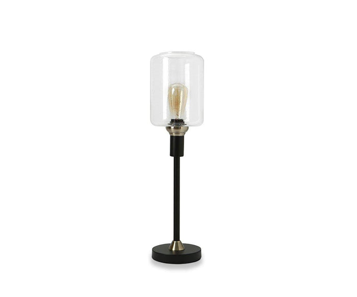 Introducing the Samuel Table Lamp, featuring a sleek black base complemented by an antique brass slim stand and topped with a clear cylindrical glass shade that showcases an exposed bulb.