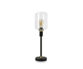 Introducing the Samuel Table Lamp, featuring a sleek black base complemented by an antique brass slim stand and topped with a clear cylindrical glass shade that showcases an exposed bulb.