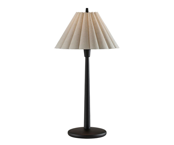 The Scallop Table Lamp, featuring a slender black base and a pleated beige lampshade, is photographed against a white background and emits a warm glow to enhance any setting.