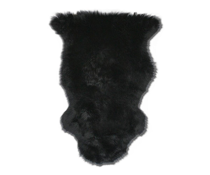 The Sheepskin Throw - Black features an irregular, animal-hide shape and is crafted from luxurious New Zealand sheepskin in Sheepskin Black, shown against a white background.