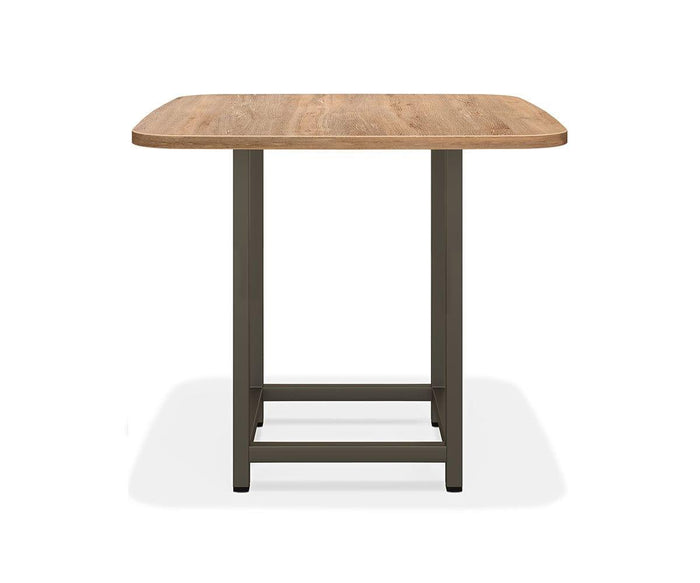 The Slater Bar Height Square Meeting Table, in Oak Driftwood, features a wooden square top with rounded corners and sleek metal legs. Viewed from the front against a plain white background, this table highlights the natural elegance of its wood grain finish.