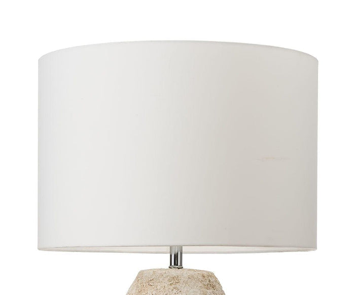 The Stone Shores Table Lamp - Tall features a white cylindrical lampshade paired with a small visible portion of its beige, textured base, offering a rustic yet elegant touch to modern home decor, shown here against a plain white background.