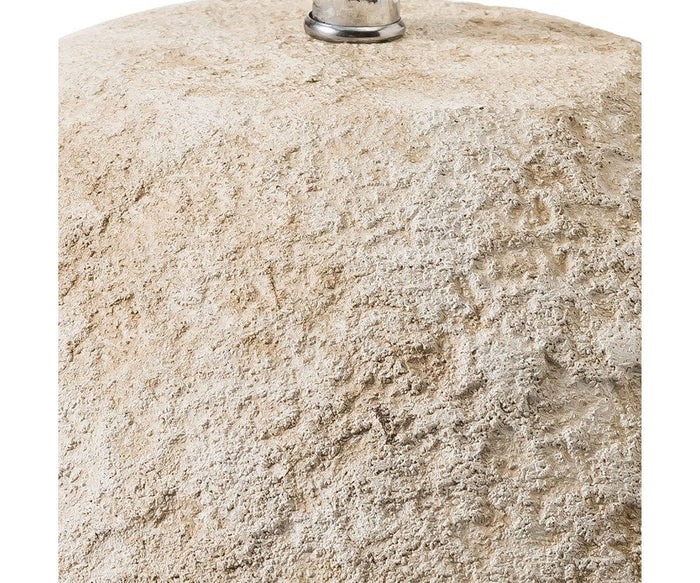 Close-up of a rough, sandy, beige textured surface—possibly stone or cement—with a small, shiny metallic fixture at the top center. The natural look evokes modern home decor trends, making it an ideal backdrop for showcasing the Stone Shores Table Lamp.