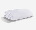 A neatly folded white Stretchwick Mattress Protector rests on a plain white background, casting a soft shadow.