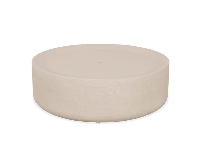 The Taneli Outdoor Coffee Table features a round, taupe concrete design with a smooth, minimalist silhouette and a flat top surface, showcasing modern organic textures reminiscent of faux travertine.