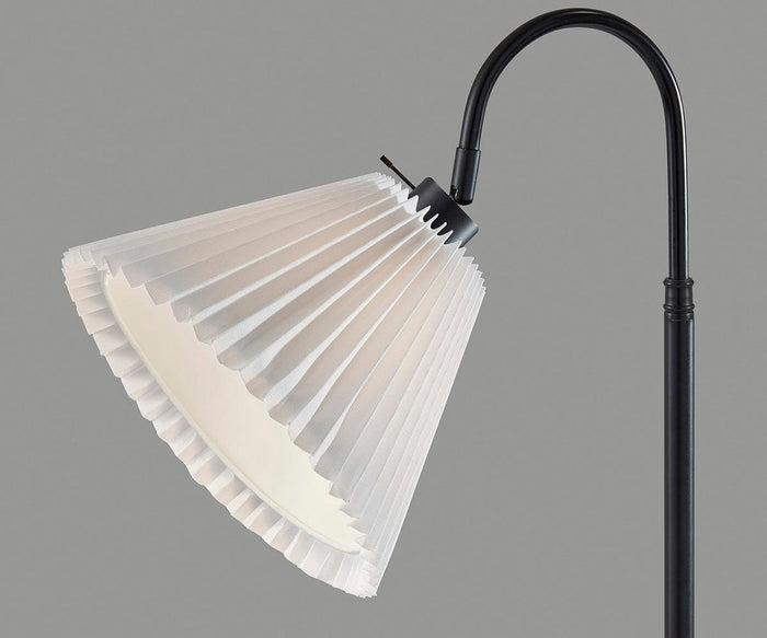 A modern accent piece, the Thalia Table Lamp features a gracefully curved black neck and a white pleated lampshade, set against a plain gray background.