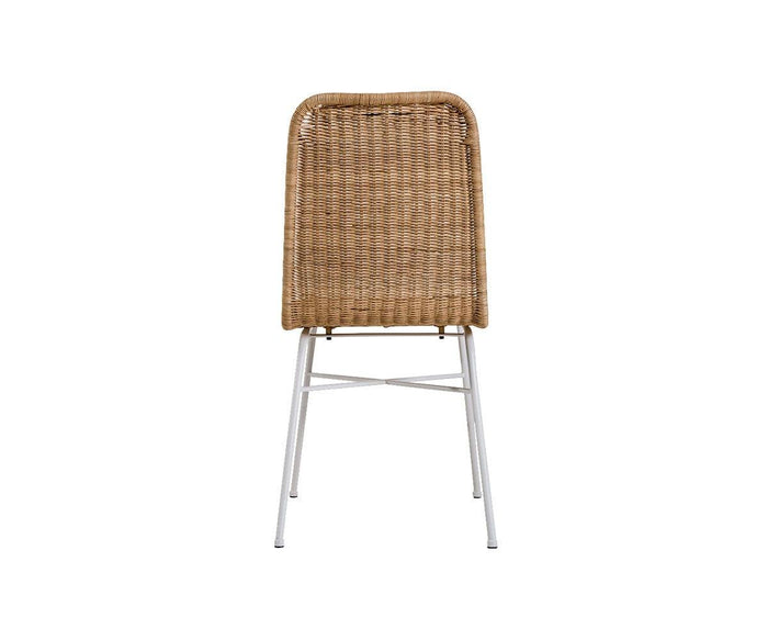 The Tori Dining Chair features a woven rattan construction with a rounded backrest and four white metal legs. Viewed from behind against a plain white background, this modern dining chair combines sleek lines with a natural aesthetic.