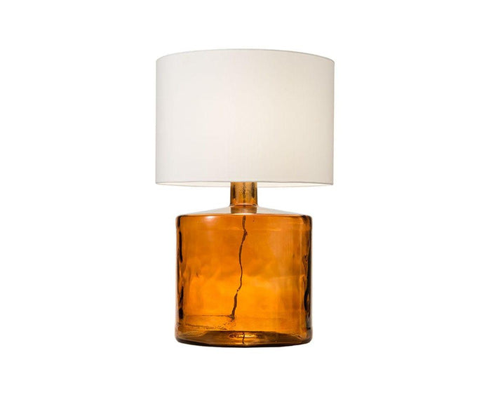 The Translucent Glass Lamp - Amber features a round base crafted from recycled, amber-toned glass and is topped with a large white fabric shade, set against a plain white background.