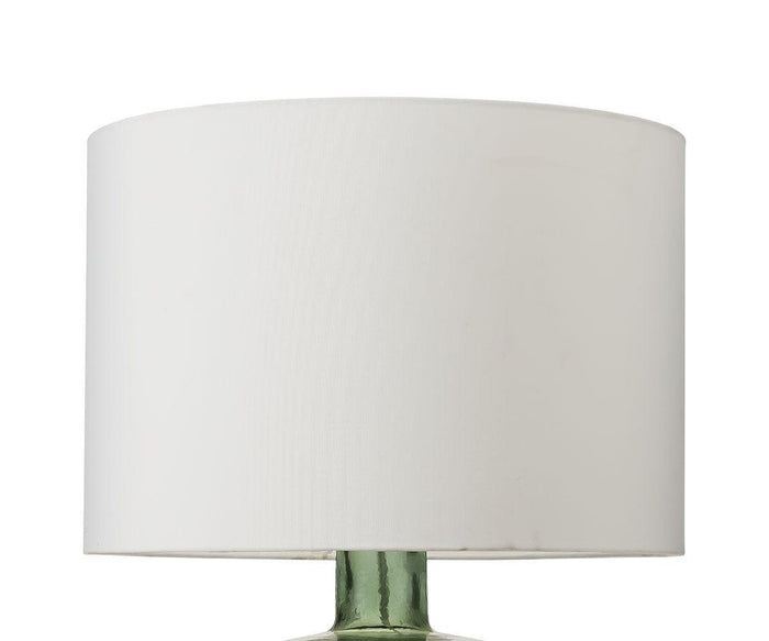 A white fabric drum-shaped shade sits atop the Translucent Glass Lamp - Smokey Grey, offering a partial view of its smokey grey recycled glass base against a plain white background.