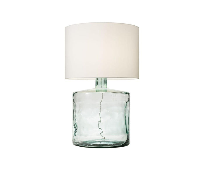 The Translucent Glass Lamp features a wide, cylindrical fabric shade and a transparent, light green glass base with visible wiring inside. Its modern, minimalist design adds a contemporary touch to any space.