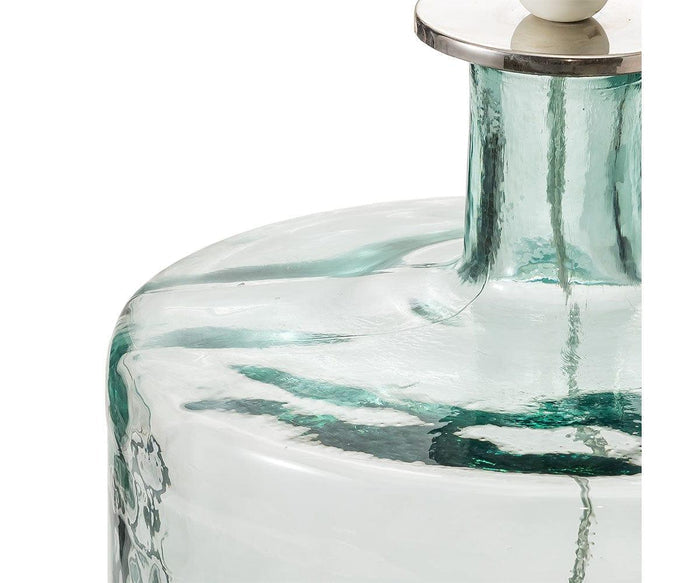 Close-up of the Translucent Glass Lamp, featuring a clear glass bottle with a thick neck and subtle greenish tint. The upper portion is shown, highlighting the smooth surface with visible reflections and a round, metal-topped stopper.