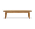 Crafted from solid natural teak, the Vinicio Outdoor Bench showcases a simple design with an oval-shaped seat and four angled legs, making it a standout piece of modern outdoor furniture displayed against a white background.