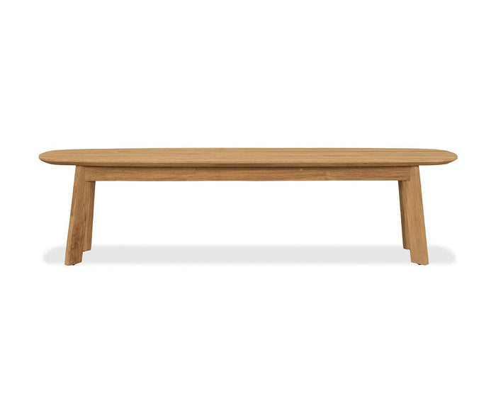 Crafted from solid natural teak, the Vinicio Outdoor Bench showcases a simple design with an oval-shaped seat and four angled legs, making it a standout piece of modern outdoor furniture displayed against a white background.