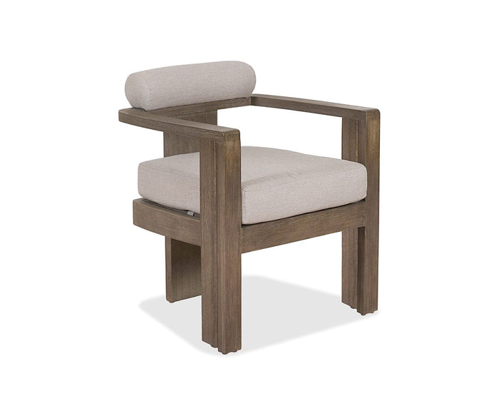 The Vinna Outdoor Dining Chair features a contemporary wooden design with thick, square legs and arms. It includes a light beige upholstered seat and a cylindrical backrest cushion, offering both comfort and style. With its minimalist aesthetic and weather-resistant construction, this chair is a modern addition to any outdoor furniture collection.