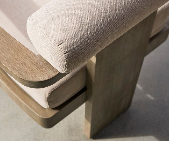 Close-up of the Vinna Outdoor Dining Chair, featuring beige upholstery and a wooden frame, with attention to the armrest and seat illuminated by natural light—an elegant example of high-quality, weather-resistant modern outdoor furniture.
